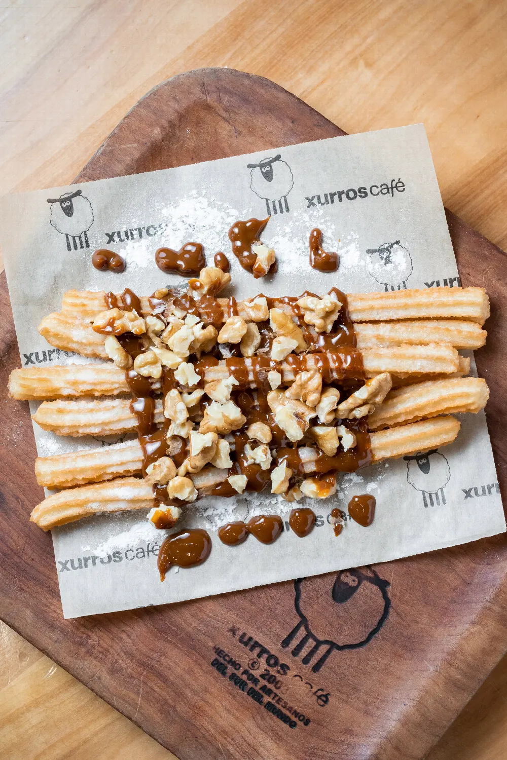 Churros cubiertos con salsa y nueces sobre papel Xurros Café