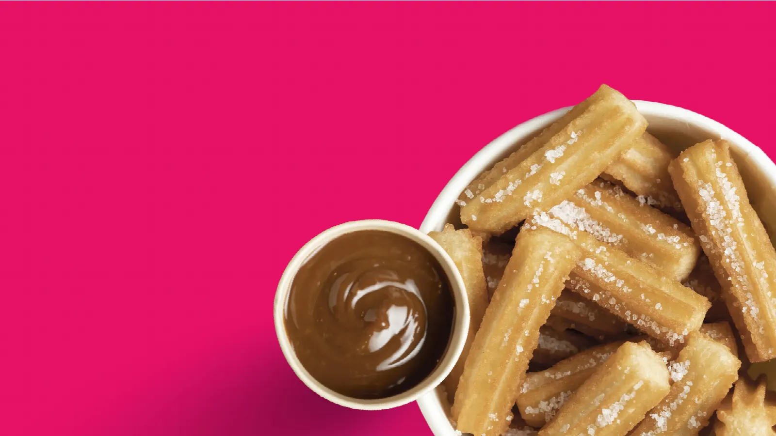 Churros en un bowl con salsa de chocolate sobre fondo rosado